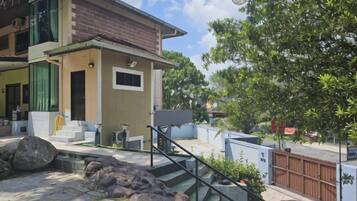 A two-story house with a staircase, outdoor seating, and a fenced yard.