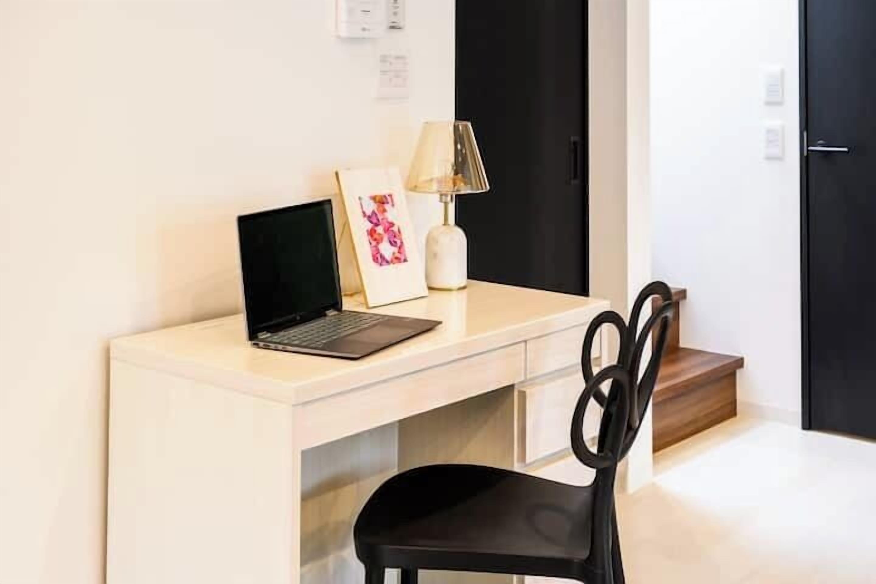 A modern office space with a desk, a laptop, a lamp, and a framed picture.