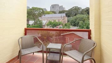 Un balcón con muebles de mimbre y vistas a un edificio y árboles.