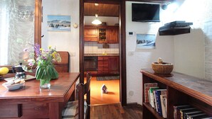 A cozy kitchen with wooden cabinets, a dining table with a vase of flowers, and a bookshelf with books. - Beautiful  villa for 6 guests with WIFI, TV, terrace and pets allowed (Nevegal)