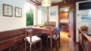 A cozy kitchen with wooden furniture, a dining table, and a hanging light fixture. - Beautiful  villa for 6 guests with WIFI, TV, terrace and pets allowed (Nevegal)