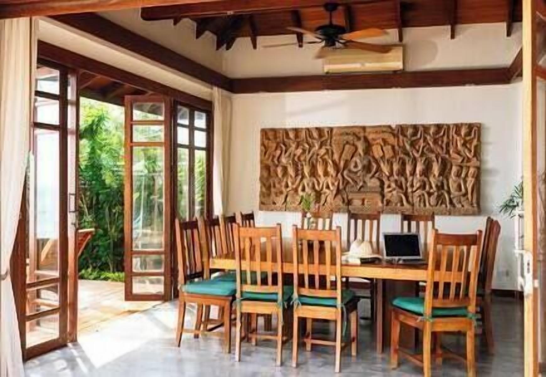 A dining area with a wooden table and chairs, a ceiling fan, and a wall with a textured design.