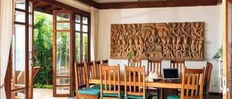 A dining area with a wooden table and chairs, a ceiling fan, and a wall with a textured design.