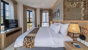 A hotel room with a large bed, a TV, a desk, and a decorative wall panel. - Montana Oceanside Mandalika (Central Lombok Regency)