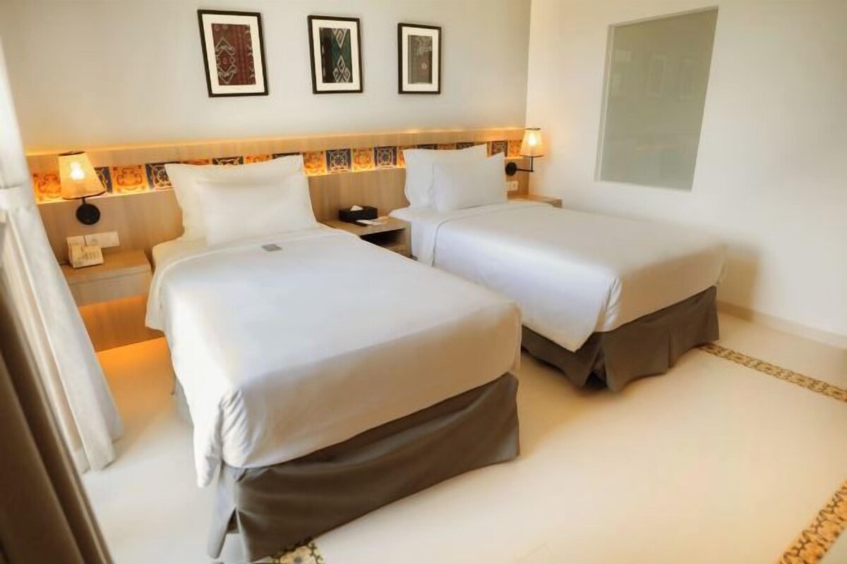 Een hotelkamer met twee bedden, een nachtkastje en een kunstwerk aan de muur.