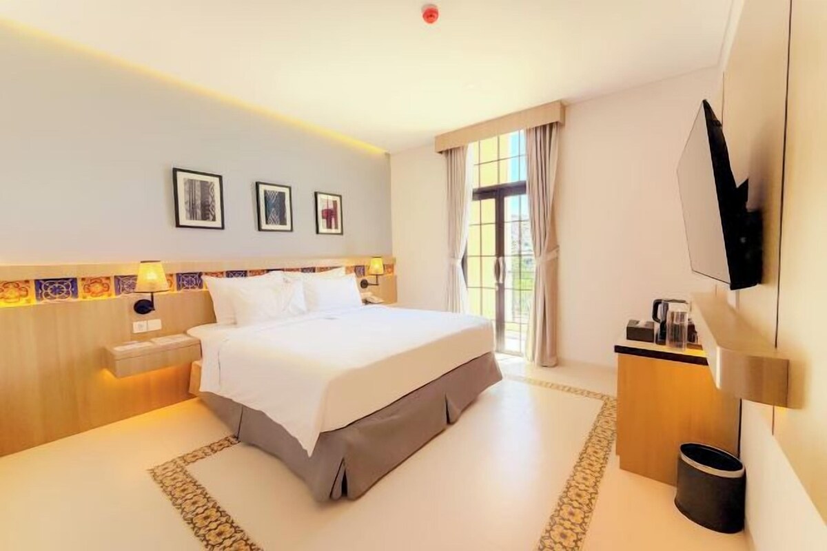 Een hotelkamer met een groot bed, nachtkastjes, een flatscreen-tv en uitzicht op de omgeving.