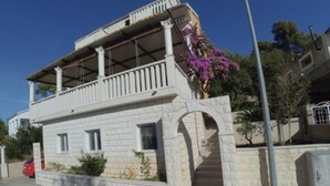 A two-story building with a balcony, a stone facade, and a small entrance. - Apartments Maritimo (Smokvica)