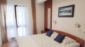 A bedroom with a bed, a wardrobe, a painting, and a window with curtains. - Apartments Maritimo (Smokvica)