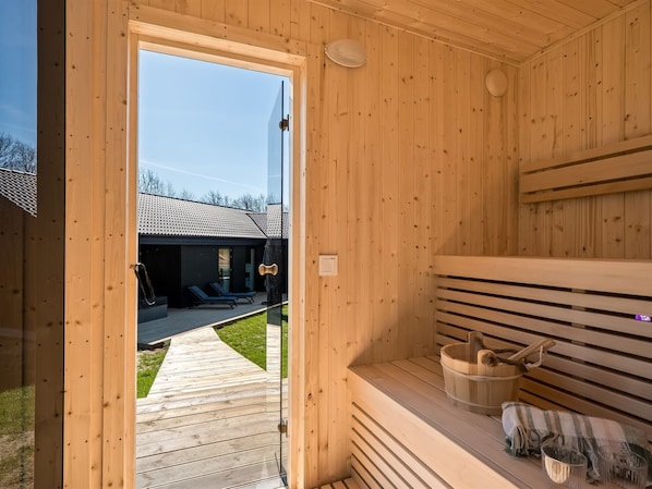 A wooden sauna room with a bench, a bucket, and a towel.