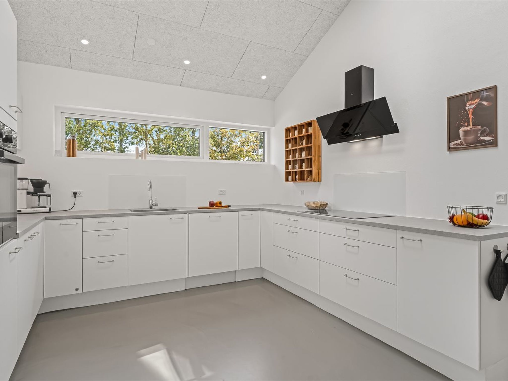 A modern kitchen with white cabinetry, a built-in oven, and a window providing natural light.
