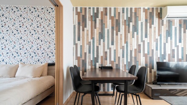 Una habitación moderna con una cama, una mesa de comedor con sillas, un televisor y una pared con diseño.