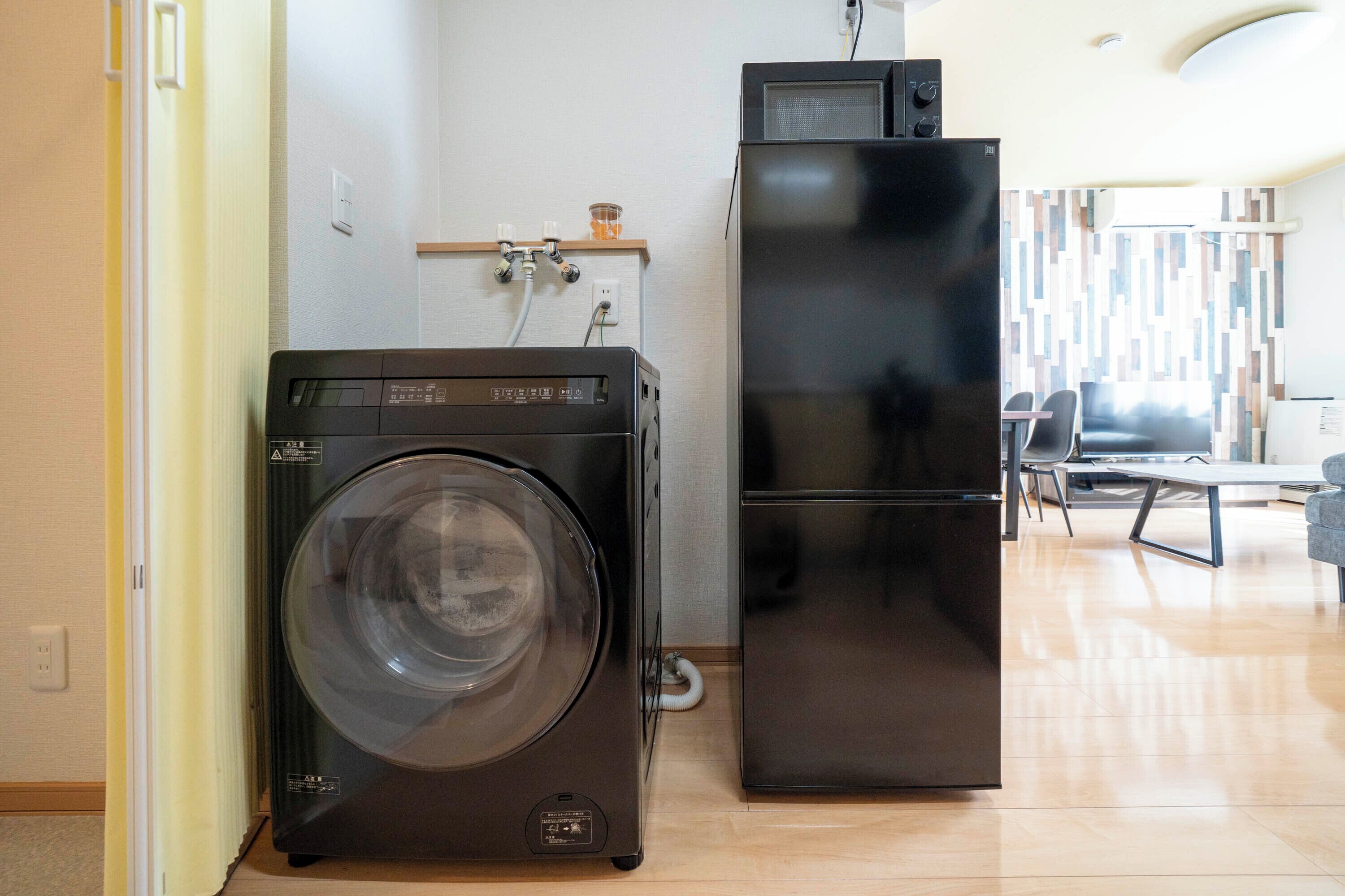Un espacio habitable compacto con lavadora, refrigerador y zona de comedor con sillas y mesa.