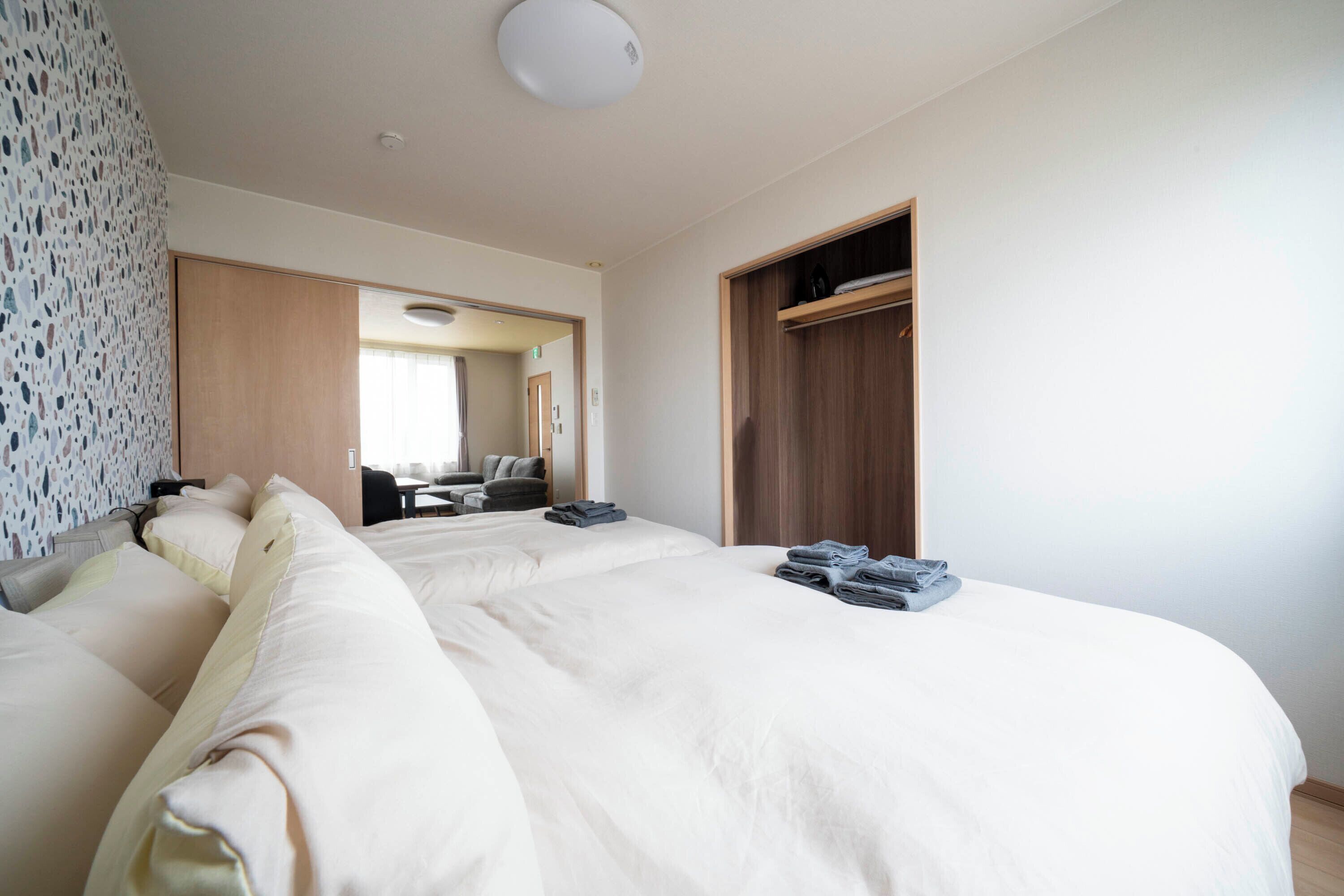 Quarto de hotel com uma cama grande, um guarda-roupa de madeira e um espaço de estar com um sofá e cadeiras.