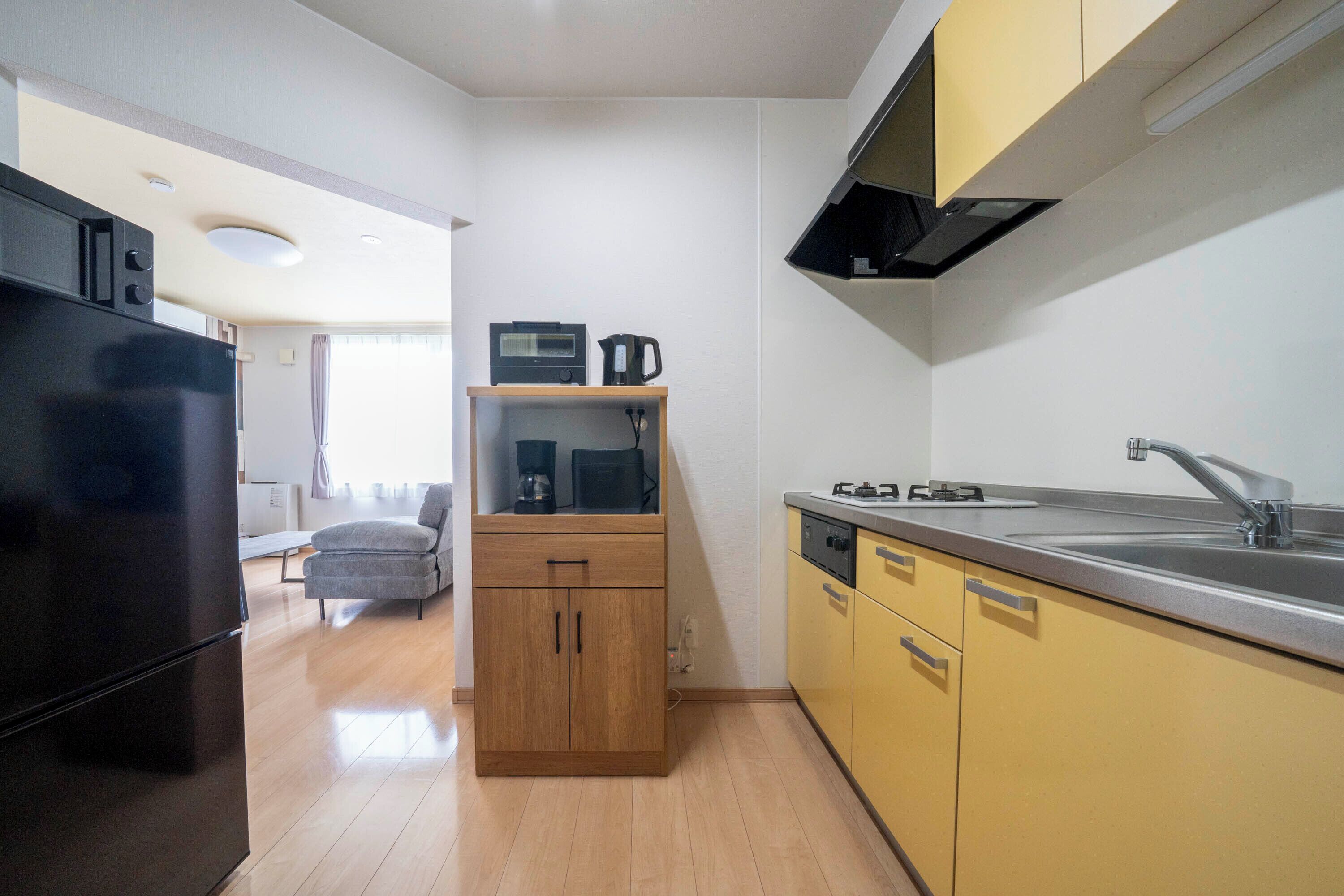 A compact kitchen with a refrigerator, microwave, coffee maker, and a sink.