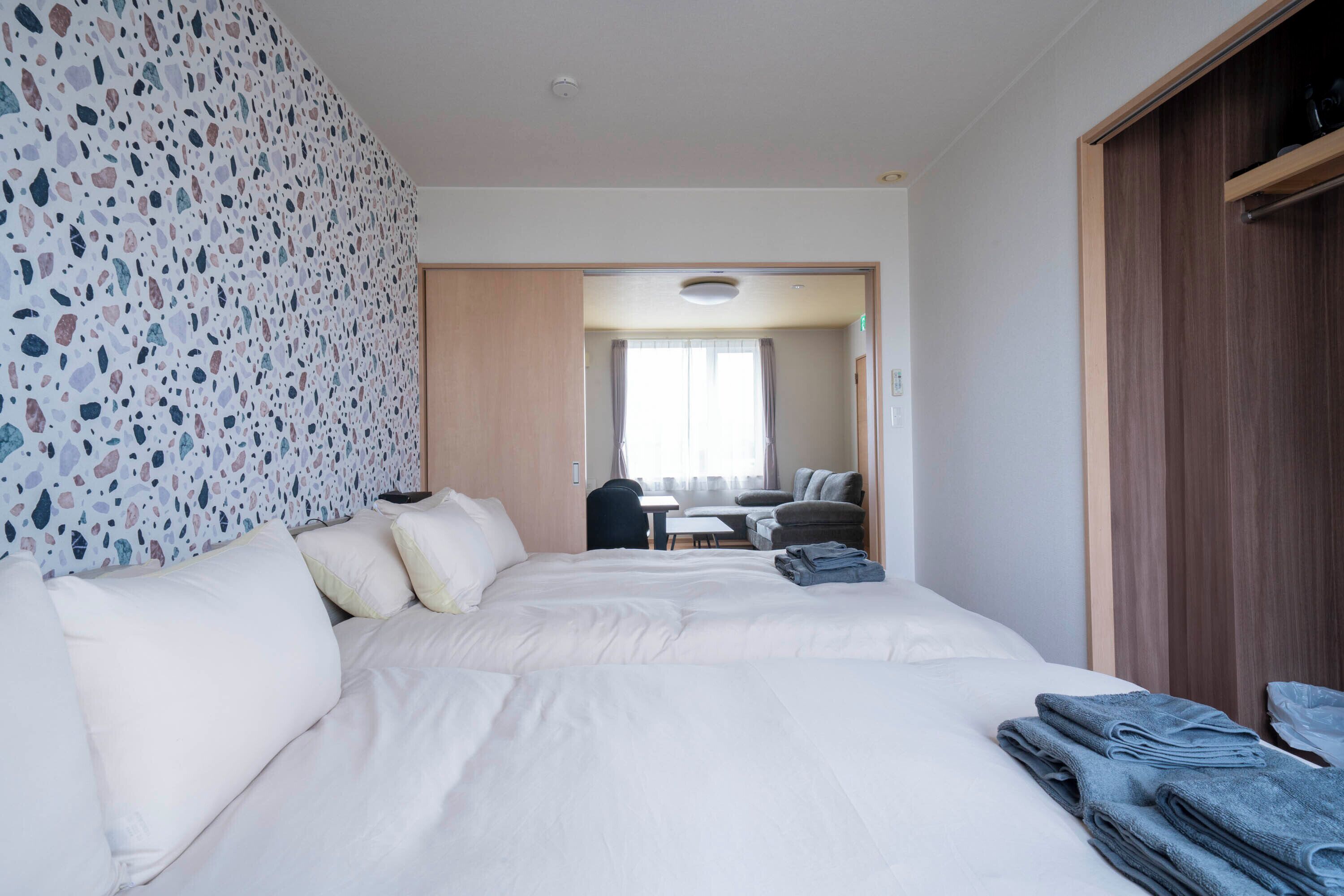 A hotel room with a large bed, a desk, a chair, and a wardrobe.