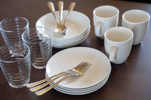 A set of white plates, forks, and cups arranged on a wooden table. - LAMBRUSCO (Kamifurano)