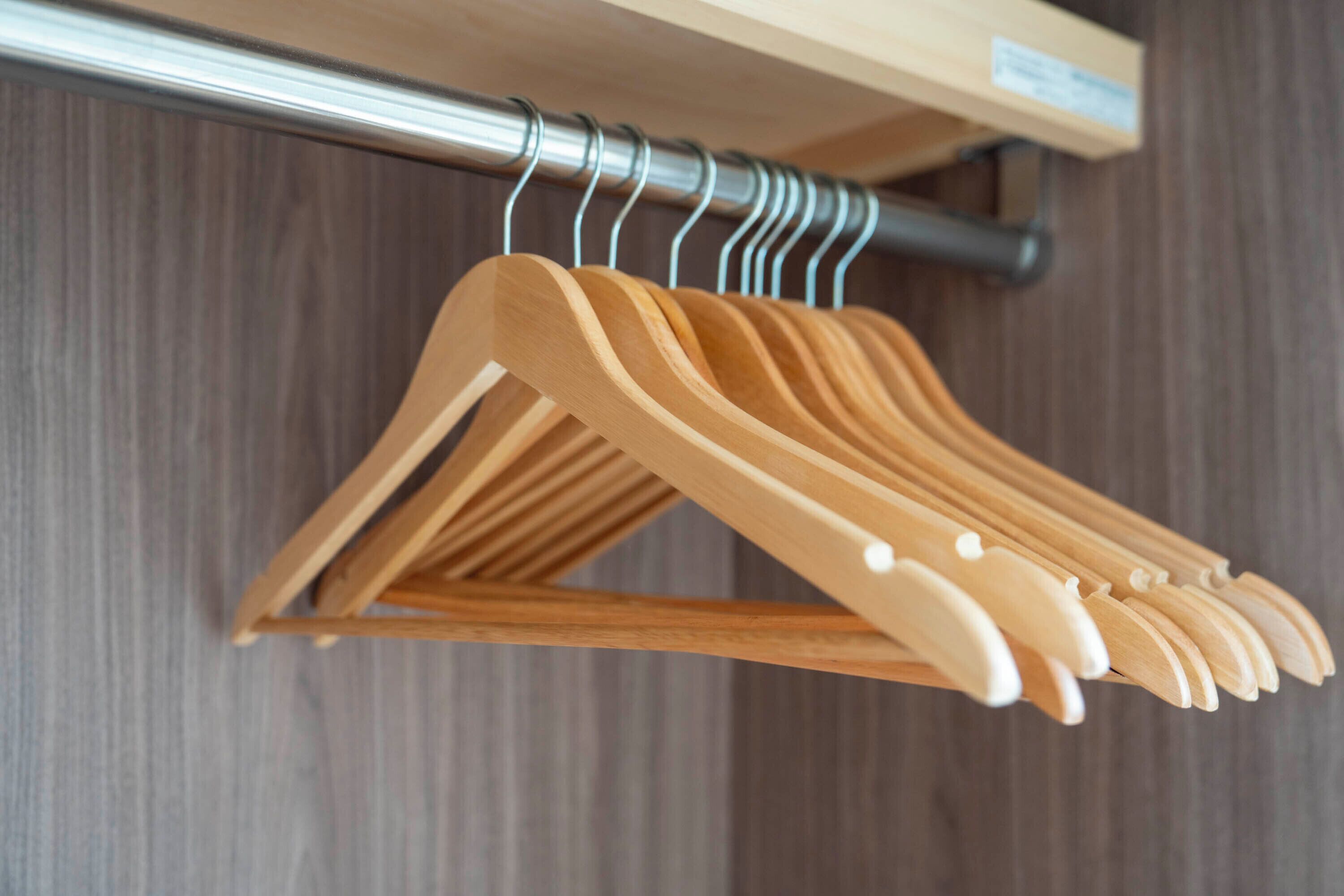 A wooden clothes rack with several hangers, mounted on a wall with a wooden panel background.