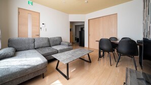 Una sala moderna con un sofá seccional gris, una mesa de centro y sillas negras.