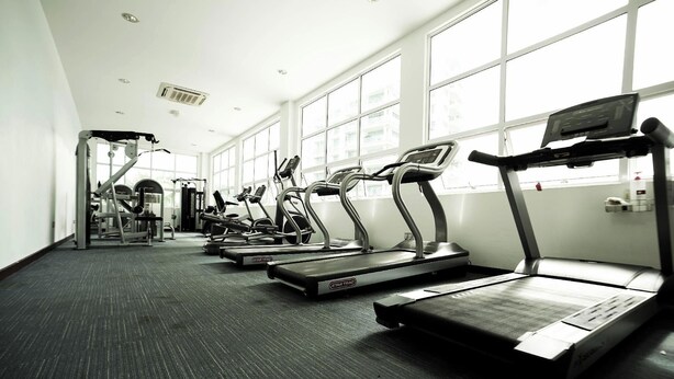 Un gimnasio con cintas de correr, elípticas y equipo de pesas.