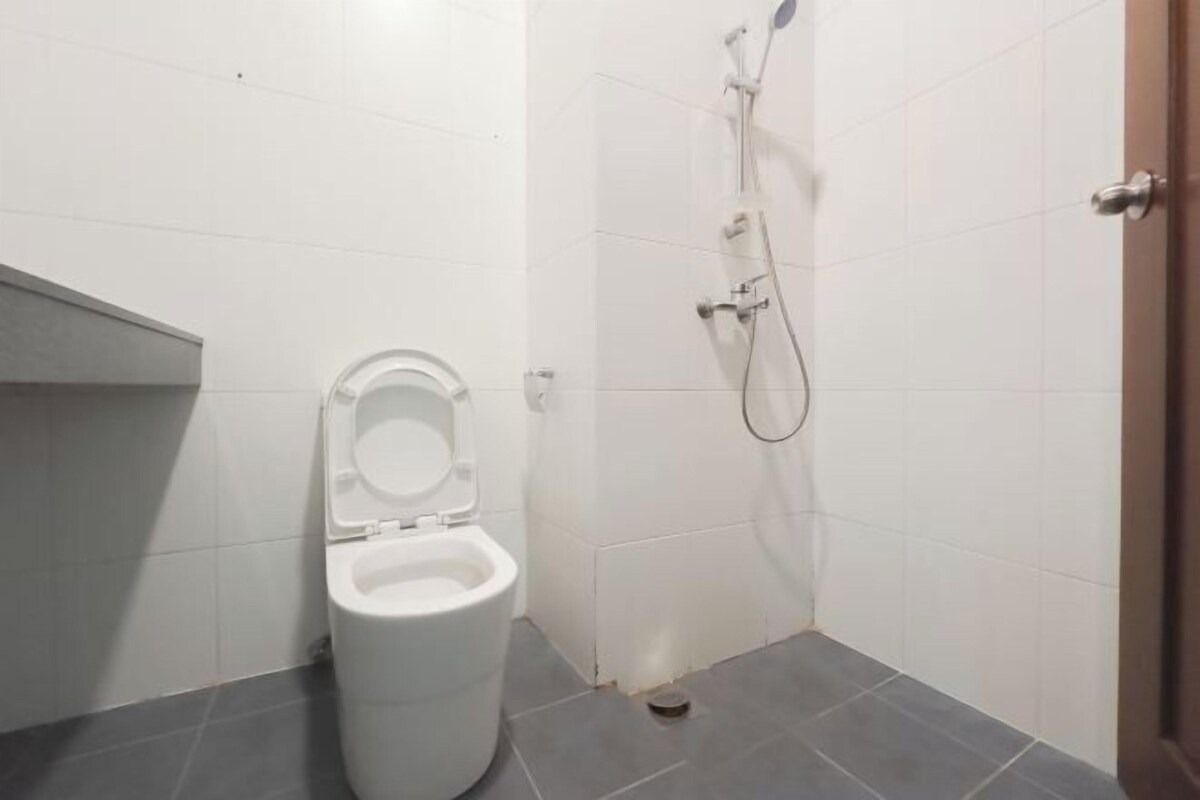 A small bathroom with a toilet, a shower, and a door.