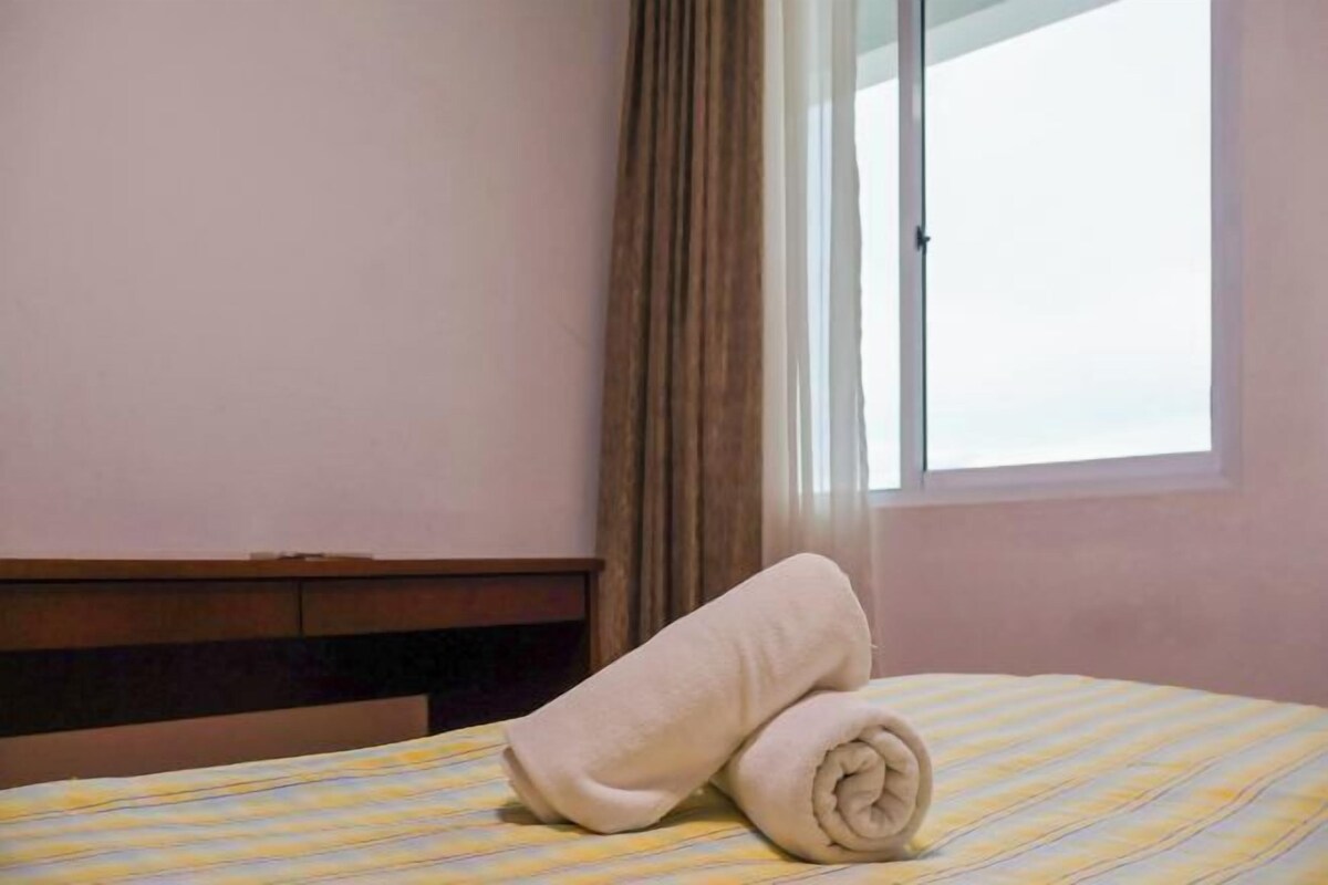 A hotel room with a bed, a window, and curtains.