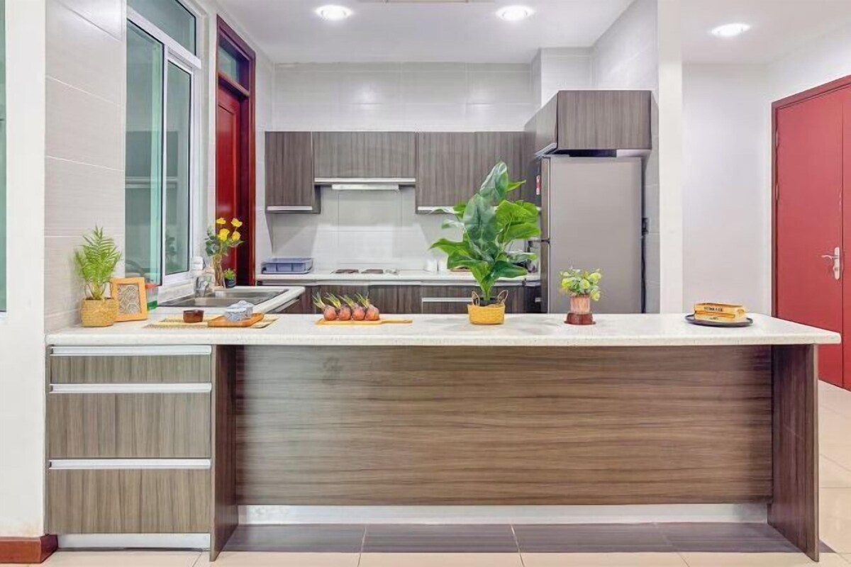 A modern kitchen with a central island, built-in cabinets, and a red door.