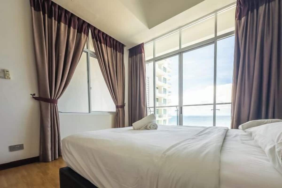 Hotellihuone, jossa on suuri ikkuna, sänky ja verhot.