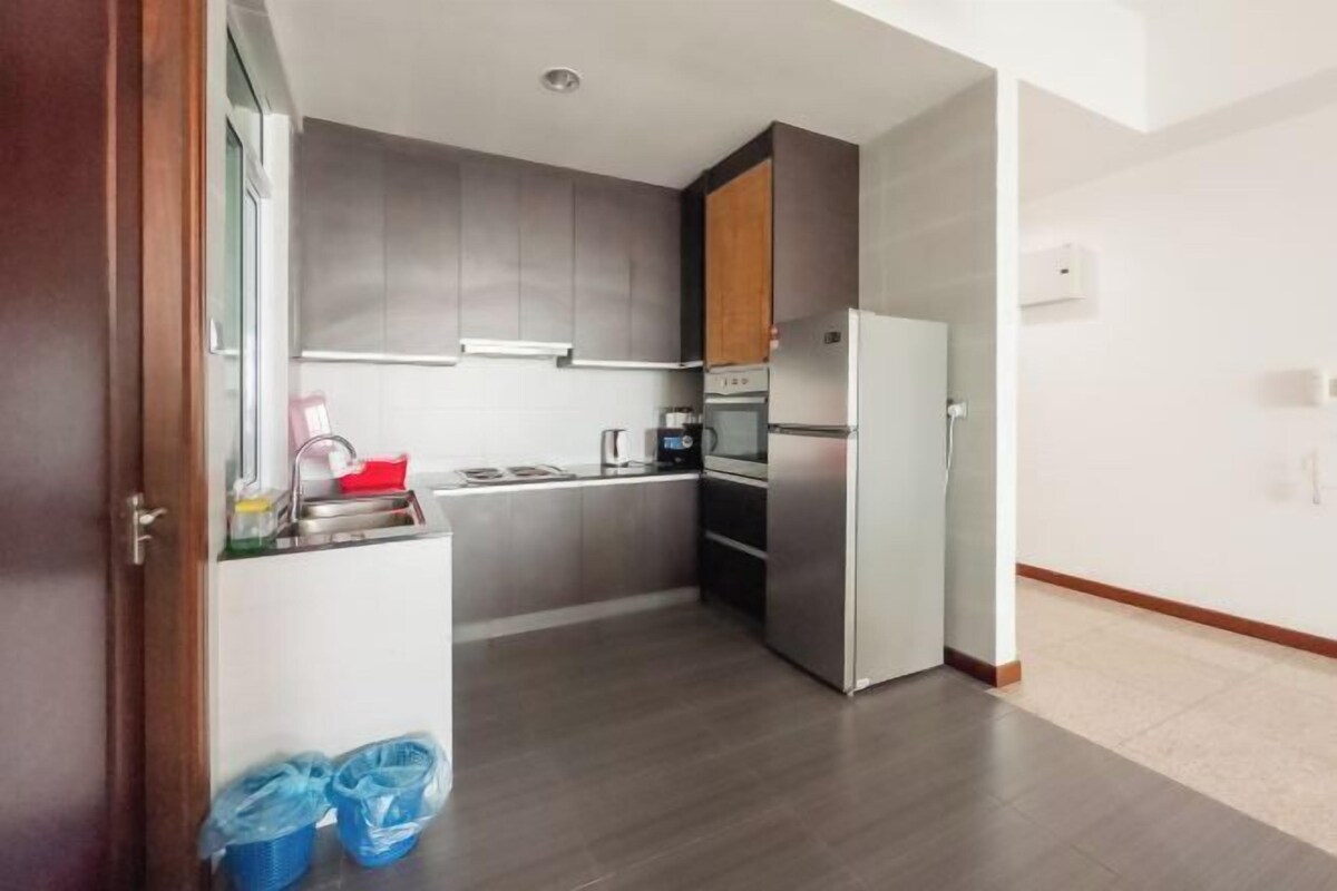 A modern kitchen with grey cabinets, a stainless steel refrigerator, and a built-in oven.