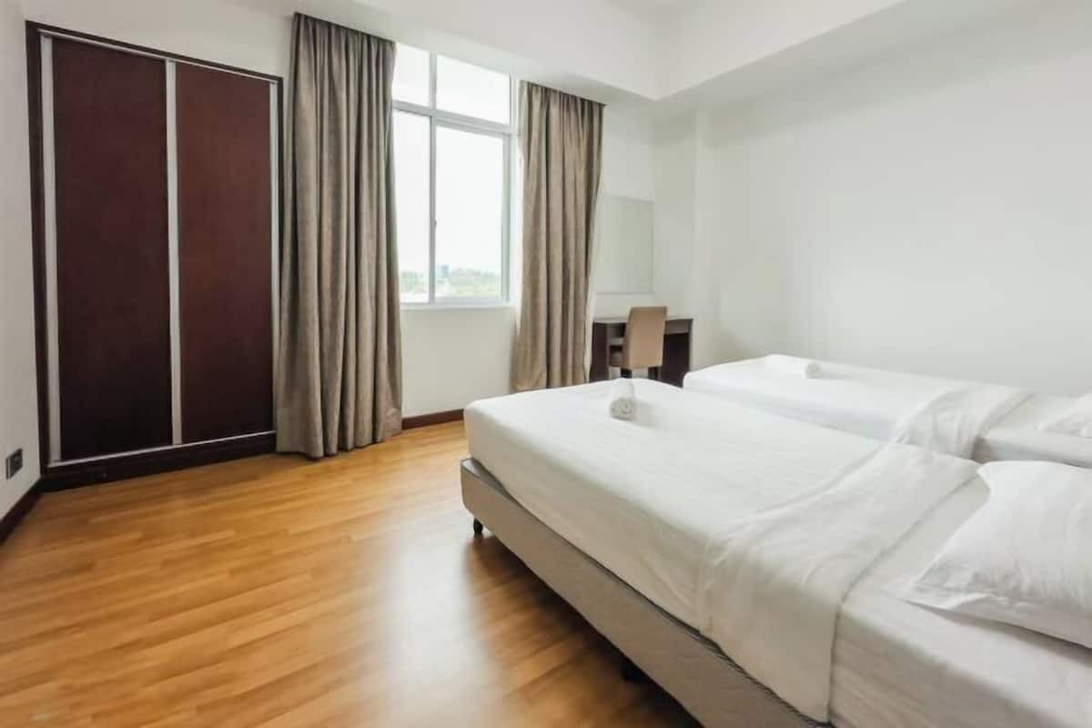 Hotellihuone, jossa on puulattia, kaksi sänkyä, vaatekaappi, työpöytä ja ikkuna, jossa on verhot.