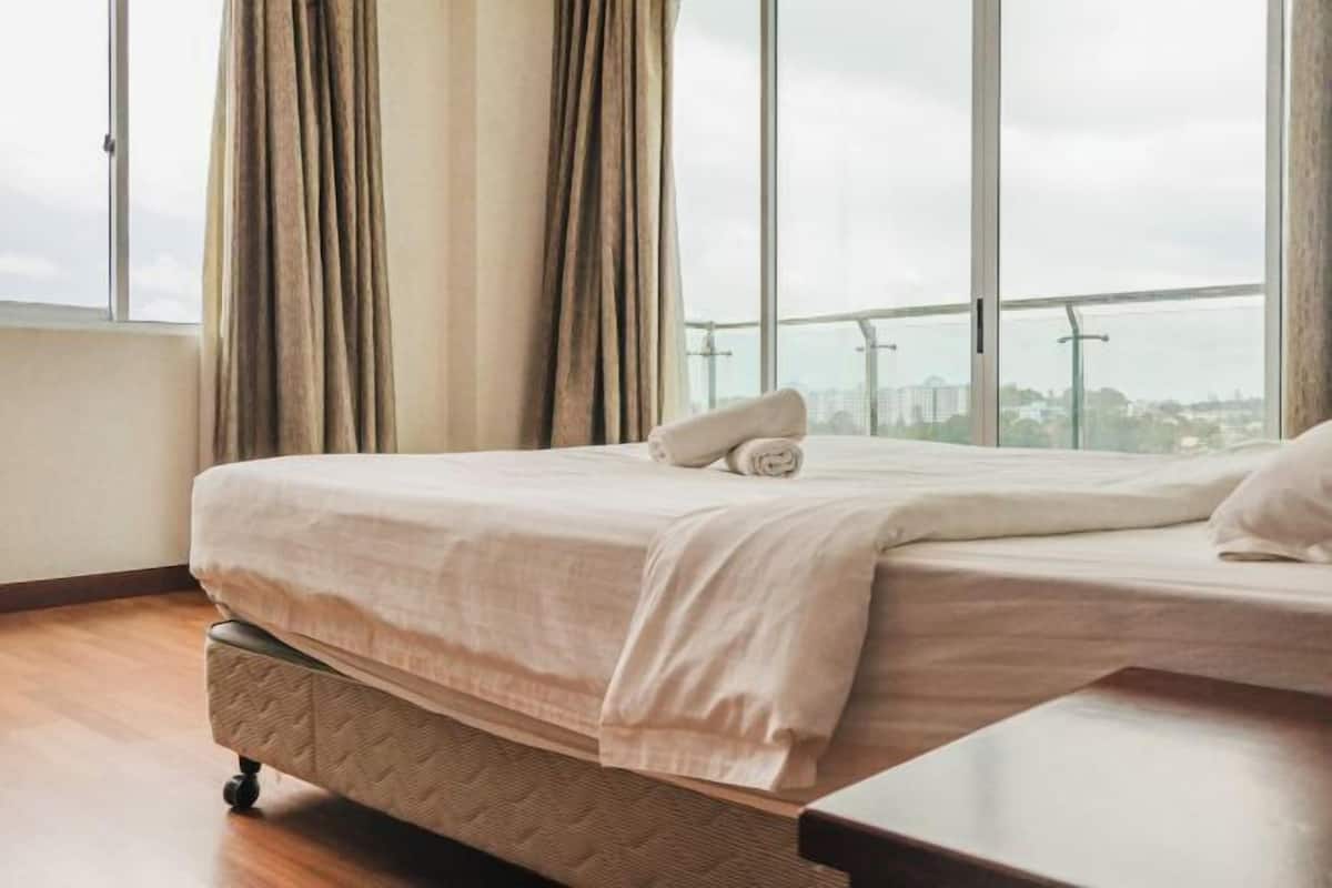 Hotellihuone, jossa on sänky, verhot ja näkymä kaupunkimaisemaan.