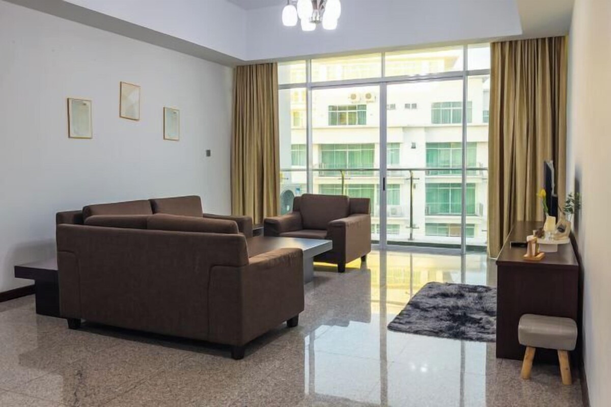 A modern living room with a sofa set, a small table, and a view of a building through large windows.