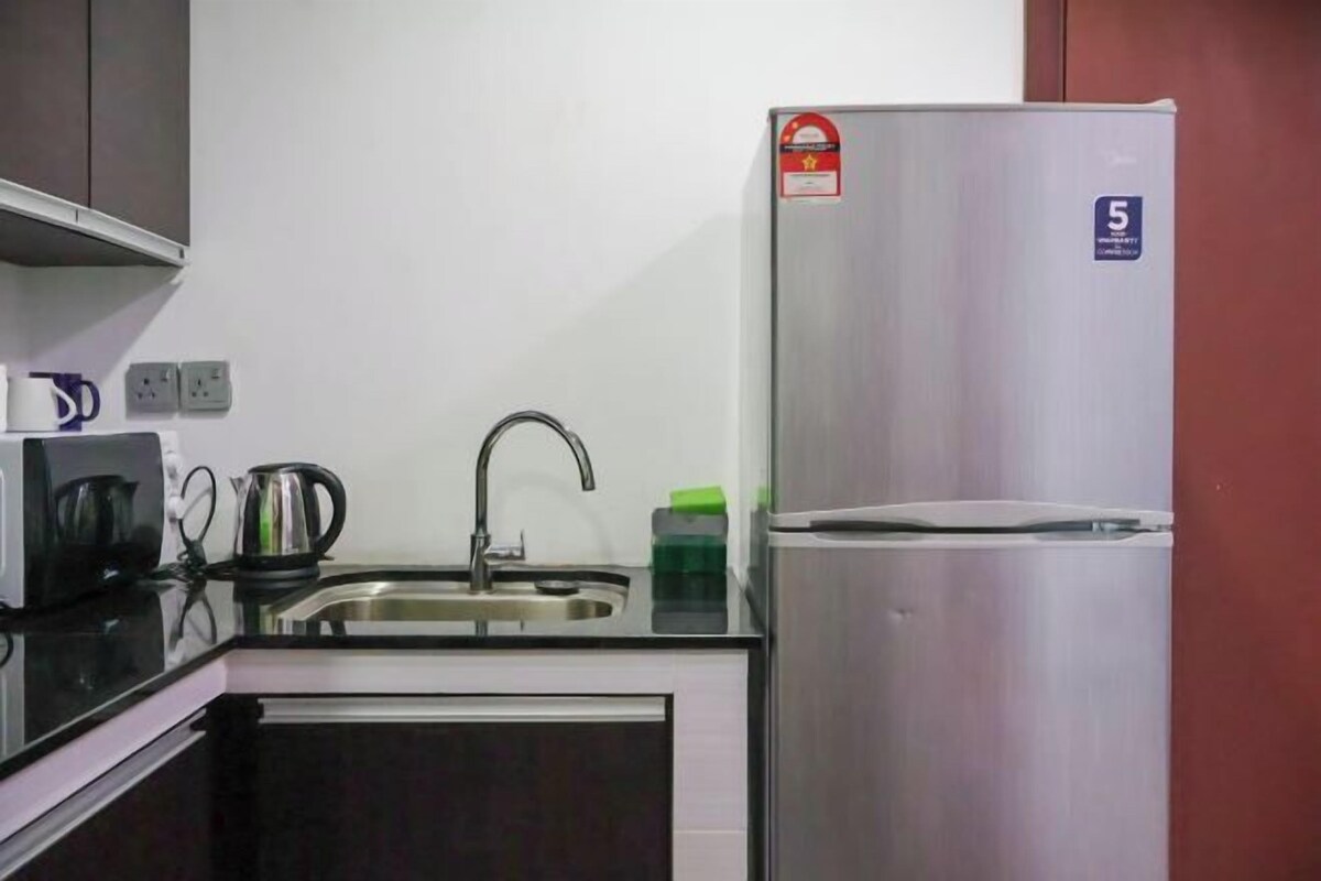 A kitchen with a stainless steel refrigerator, a sink, and a kettle.