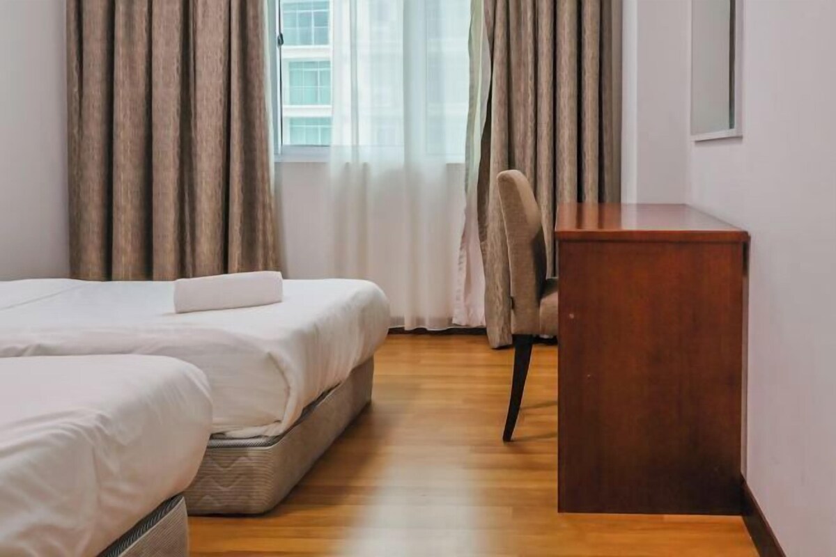 A hotel room with two beds, a desk, and a chair.