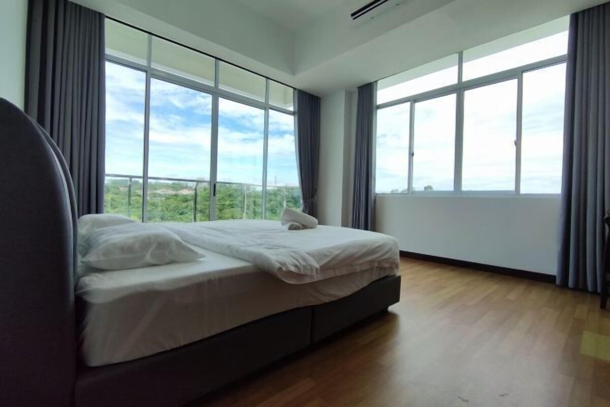 A bedroom with a large bed, a view of greenery through the windows, and a modern design.