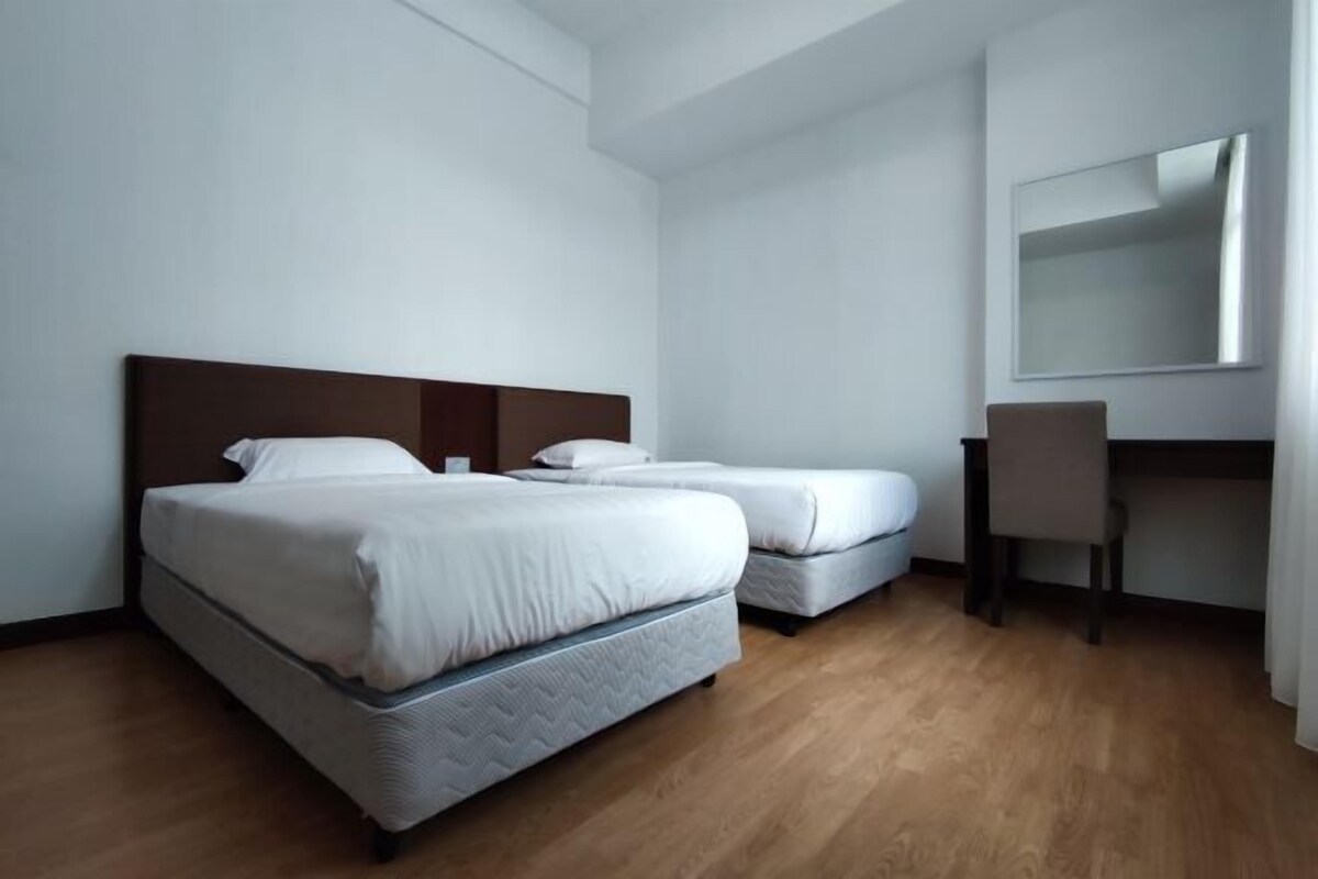 A hotel room with two beds, a desk, and a chair.