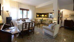 A dining area with a table set for four, a sofa, and a television in the background. - Casa Di Silvana (Rome)