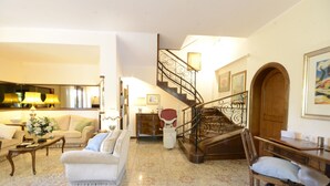 A spacious living room with a sofa, coffee table, and a staircase leading to an upper floor. - Casa Di Silvana (Rome)