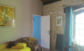 A room with a bed, a chair, a door, and a window with curtains.