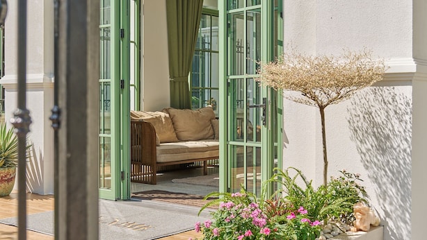 A conservatory with a curved glass door, a cushioned bench, and a planter with flowers. - Luxury 4 bedroom Solar Villa (Phu Quoc)