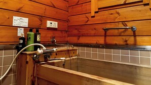 Ein Badezimmer einer Holzhütte mit einer Holzwanne, einem Fenster und einem Handtuchhalter.