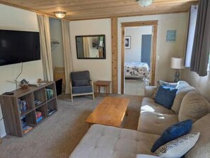 A living room with a sofa, a coffee table, a TV, a bookshelf, and a mirror.