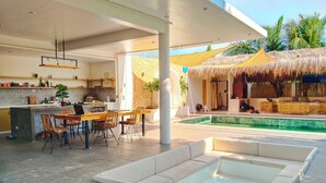 Un espace de vie extérieur moderne comprenant une piscine, un coin salon et une cuisine.