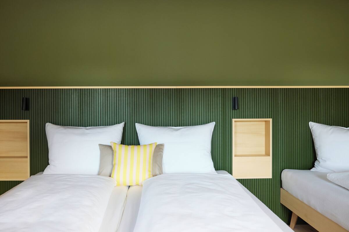 A double bed with white bedding and a yellow striped pillow, flanked by two bedside tables with wooden tops and black handles.