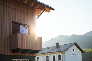 A building with a wooden facade and a balcony with a person.