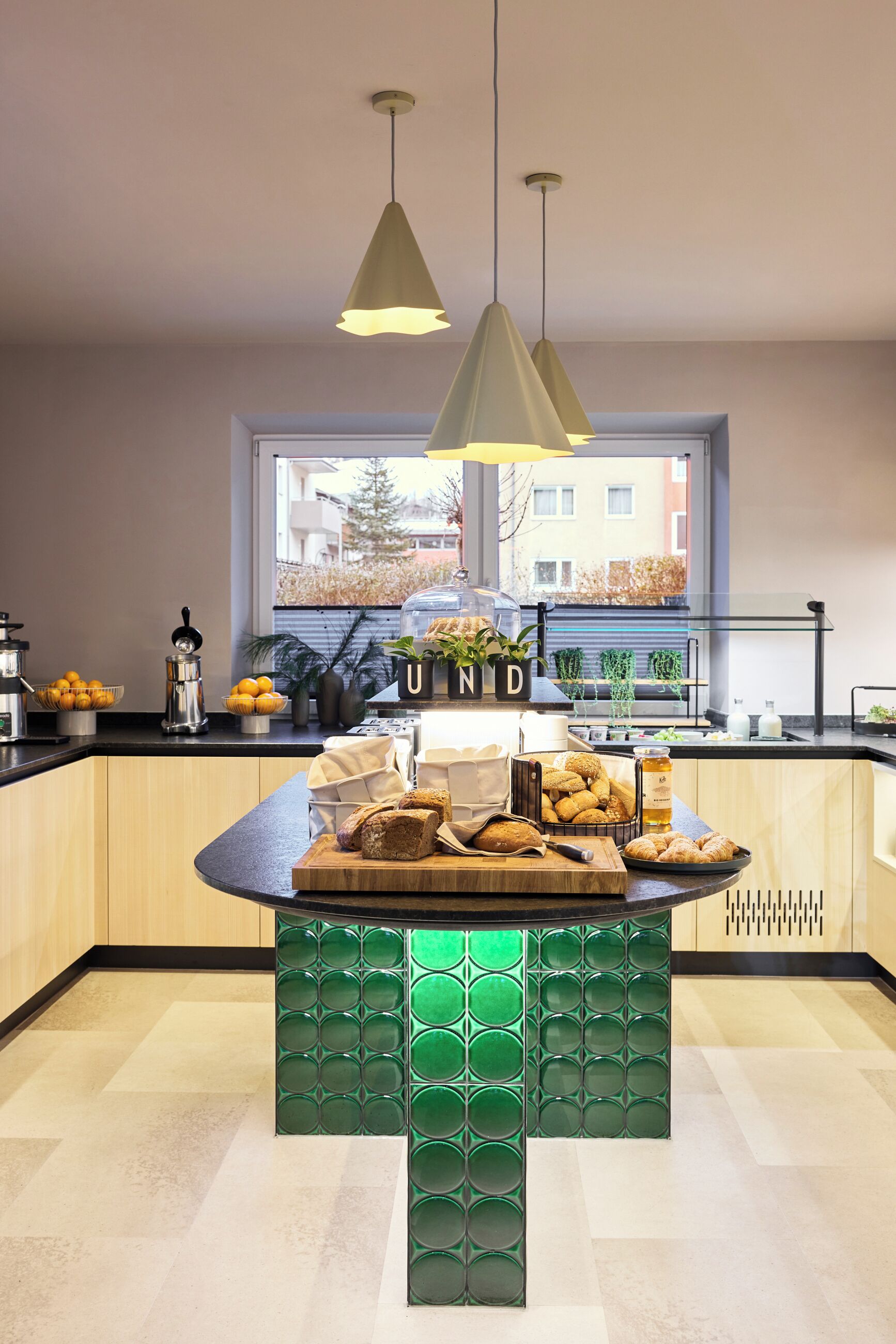 Una cocina moderna con una isla central, iluminación colgante y vistas de la ciudad a través de un amplio ventanal.