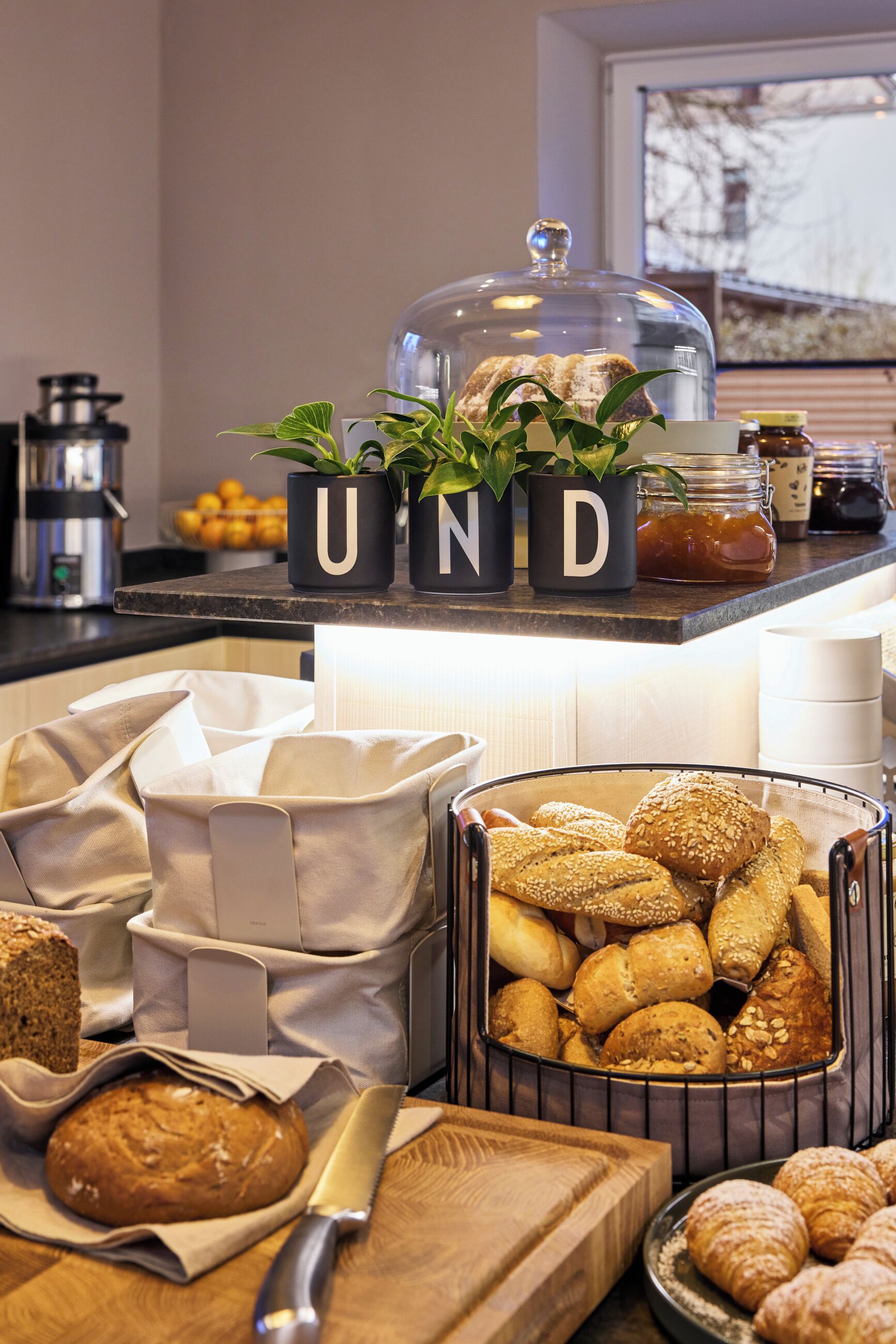 A breakfast buffet with various breads, pastries, and a coffee machine.