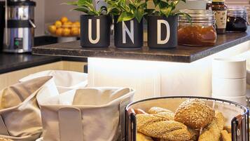 A breakfast buffet with various breads, pastries, and a coffee machine.