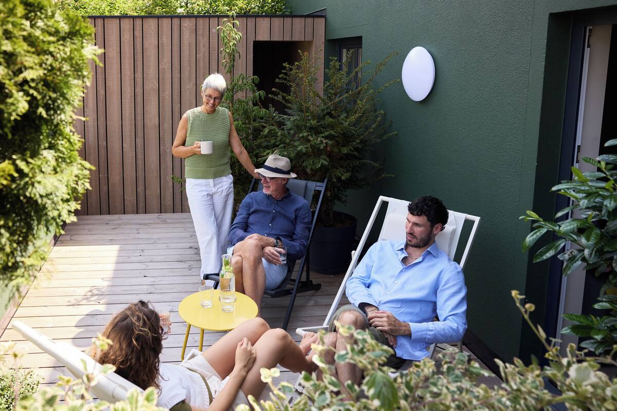 A patio area with a wooden deck, a green wall, and a white circular light fixture.