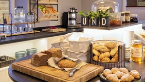 A breakfast buffet with various breads, pastries, and condiments. - Hotel UND smart alpine stay (Schladming)