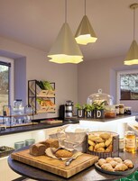 A breakfast buffet with various breads, pastries, and condiments.